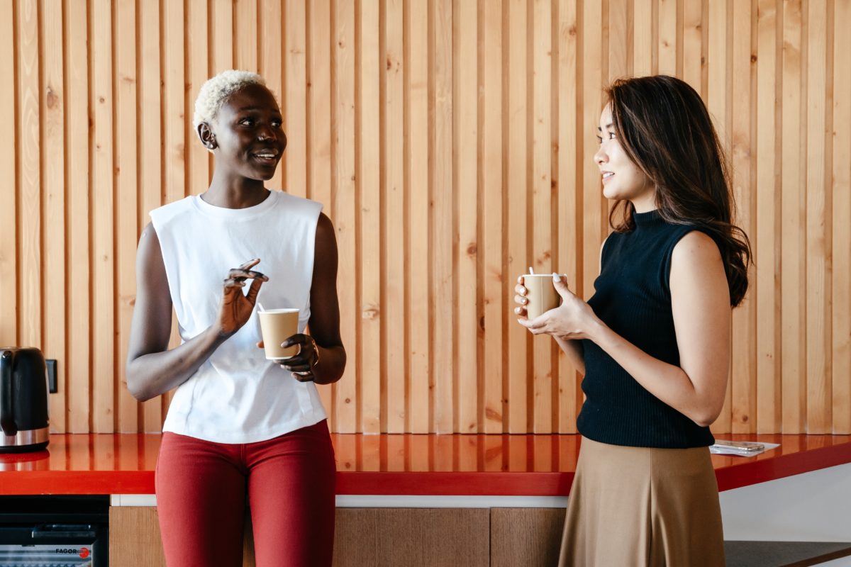 Two women holding coffee cups having a chat